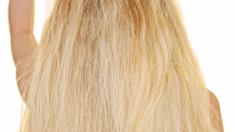 A-blond-woman-touching-her-long-hair-to-make-some-relaxing-movement-before-combing-it