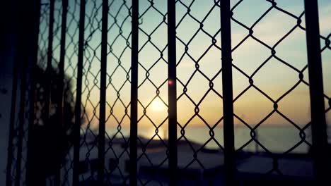 Lisbon-harbor-sunrise-with-cranes-silhouette-through-wire-fences