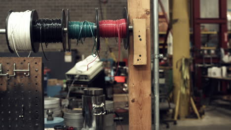 Sliding-shot-of-wire-spools-on-a-worker's-tool-bench