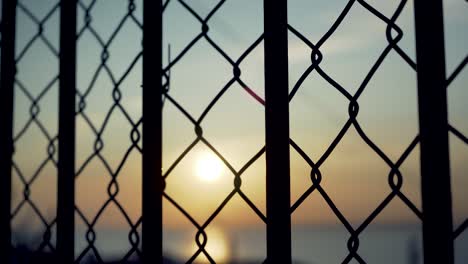 Lisbon-harbor-sunrise-with-cranes-silhouette-through-rusty-fences