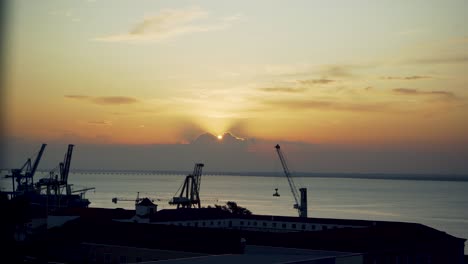 Harbor-sunrise-Lisbon-dawn-with-cranes-silhouette-through-rusty-fences