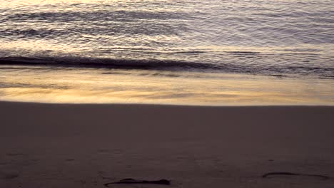 Sanfte-Wellen-Spülen-Den-Tropischen-Hawaiianischen-Strand-Mit-Fußspuren-Im-Sand-An-Land