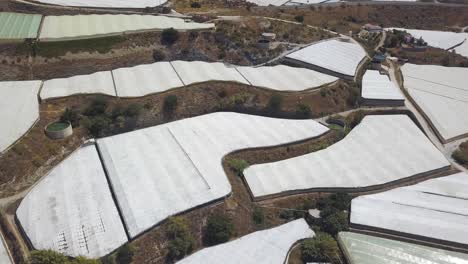 Aerial-descending-shot-over-greenhouses-in-terraces-in-a-mountain-of-the-south-of-Spain