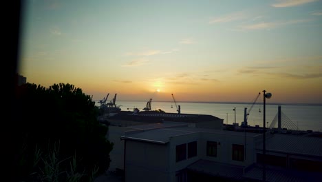 Lisbon-Harbor-sunrise-with-cranes-silhouette-through-rusty-fences