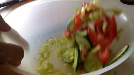 Tossing-mixed-vegetables-in-a-plastic-bowl-mixing-it-with-olive-oil