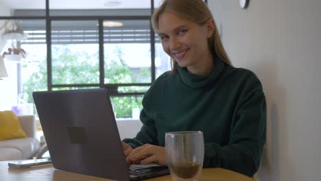 Women-using-her-Laptop-and-Smiling-to-the-Camera