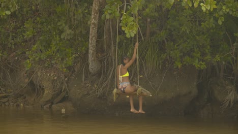 A-woman-sitting-and-swinging-at-the-rivers-edge-while-enjoying-herself