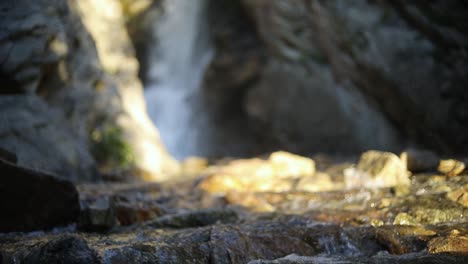 Slow-Motion-Shot-panning-up-above-a-stream-and-revealing-a-large-waterfall-in-the-Wasatch-Mountains-in-Utah
