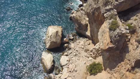 Aerial-tilt-down-shot-over-rocks-in-a-big-cliff-of-the-mediterranean-sea-in-Spain