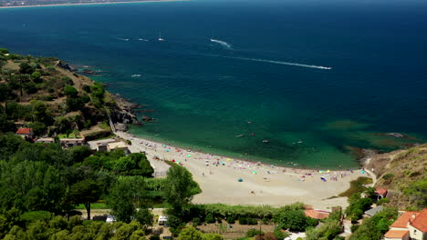 Aerial-shot-of-a-beach-with-people-near-Collioure-at-the-Mediterranean-Sea-during-a-hot-summer-day
