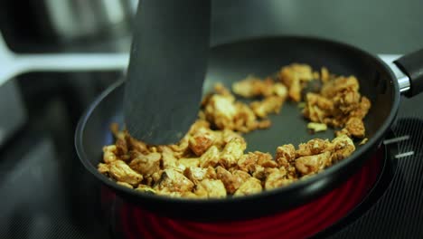 Slow-Motion-shot-of-someone-cooking-sizzling-chicken-in-a-pan-over-a-stove