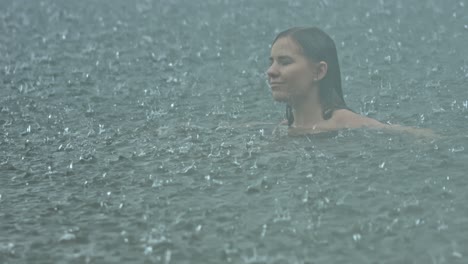 Woman-swimming-in-lake-in-hot-summer-rain