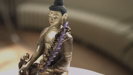 4K-Slider-shot-of-golden-Buddha-statue-with-prayer-beads-shallow-depth-of-field