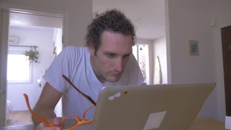 Man-working-on-a-computer-at-home-having-difficulties-to-see