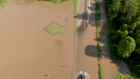 4k-aerial-view-revealing-a-car-driving-through-the-flood-water-from-the-bottom-to-the-top