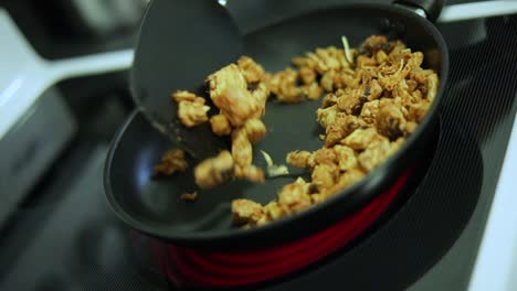 Slow-Motion-shot-of-someone-cooking-sizzling-chicken-in-a-pan-over-a-stove