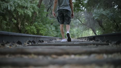 Slow-Motion-Shot-of-a-lonely-man-walking-on-abandoned-Train-Tracks