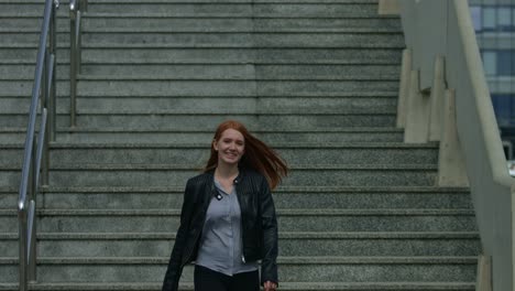 A-beautiful-young-red-haired-woman-smiles-and-walk-to-camera-the-great-concrete-city-stairs