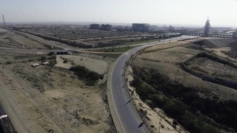 An-aerial-slow-mo-view-of-a-highway-and-city,-The-heavy-trawlers-and-cars-are-moving-on-the-highway,-an-interchange-is-connecting
