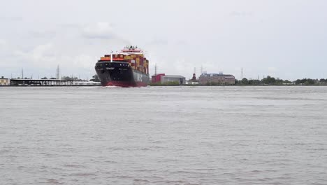 A-fully-loaded-container-ship-maneuvers-the-big-bend-in-the-Mississippi-River-at-New-Orleans,-Louisiana