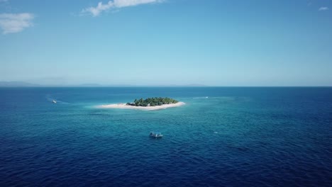 Disparo-De-Drones,-Volando-Desde-Lejos-Hacia-Un-Barco-Con-La-Isla-Del-Mar-Del-Sur-Como-Fondo-En-Fiji