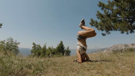 Junges-Mädchen,-Das-Yoga-Kopfstand-Auf-Einem-Berg-Durchführt