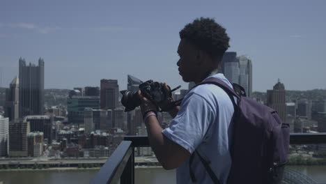African-American-male-looks-out-over-city-skyline-and-takes-photographs-stabilized-shot-in-UHD-4K