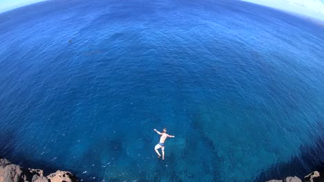 Slow-Motion-shot-of-a-man-doing-a-gainer-off-of-a-cliff-at-South-Point,-Big-Island,-Hawaii