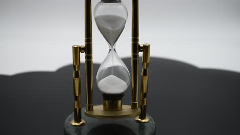 Sand-running-through-the-bulbs-of-an-hourglass-measuring-the-passing-time-on-a-black-and-white-background