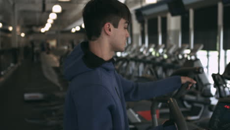 Millennial-male-using-elliptical-machine-at-his-gym-stabilized-shot-in-UHD-4K