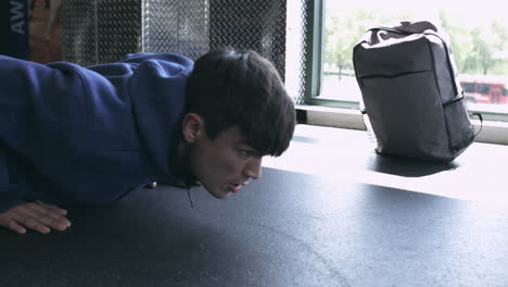 Millennial-male-doing-push-ups-in-the-gym-with-his-workout-bag-in-the-background-stabilized-shot-in-UHD-4K