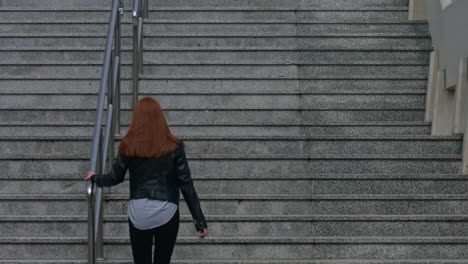 A-beautiful-young-red-haired-woman-climbs-the-great-concrete-city-stairs