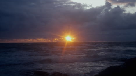 Blick-Auf-Das-Meer-Mit-Goldenen-Sonnenuntergängen,-Die-Durch-Dunkle-Wolken-Scheinen,-Statischer-Schuss