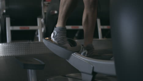 Push-in-shot-of-man's-feet-on-an-elliptical-machine-at-the-gym-stabilized-shot-in-UHD-4K
