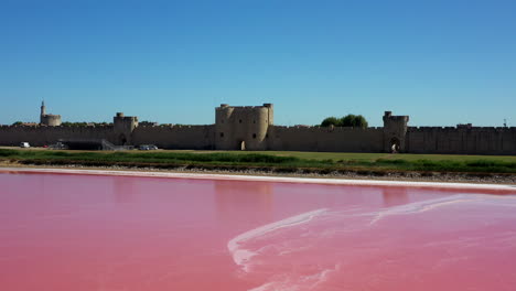 The-historical-town-of-Aigues-Mortes-in-the-Camargue,-France-during-a-sunny-summer-day-which-is-located-next-to-a-pink-salt-lake