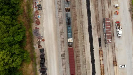 4k-top-down-view-showing-train-cars-leaving-a-train-station-withmultiple-tracks-alongside