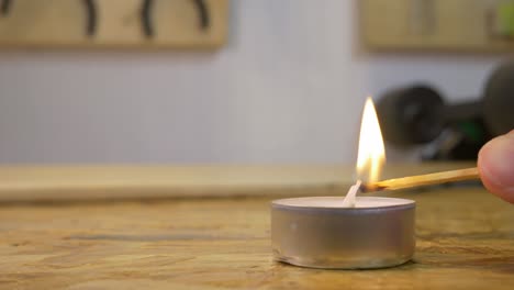 Lighting-up-a-candle-with-a-match-in-a-workshop-on-a-workbench