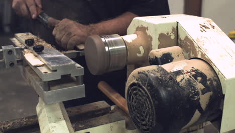 Laborer-carving-a-round-wooden-disk-on-a-lathe-with-sawdust-stabilized-slider-shot