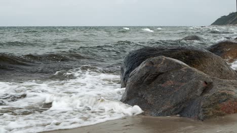 Waves-rolling-and-crashing-into-rocky-shore-on-overcast-day