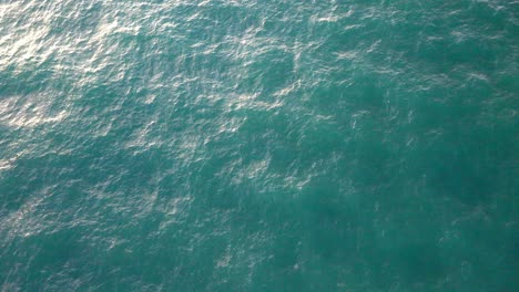 Blick-Von-Oben-Auf-Die-Wellen-In-Einem-Ruhigen-Blauen-Meer,-In-Dem-Die-Sonne-Reflektiert-Wird