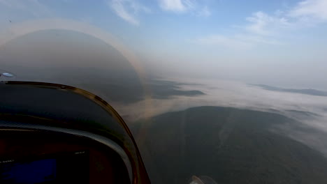 Airborne-view-from-airplane-cockpit,-fog-covered-landscape-below,-pilots-perspective-flying-cross-country,-freedom-above-the-clouds