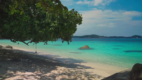 A-beautiful-4K-UHD-Cinemagraph-of-a-tropical-seaside-beach-at-Perhentian-Island,-Malaysia-with-a-tree-by-the-water-and-a-swing