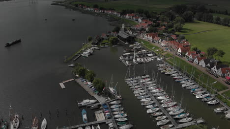 Aerial-tilt-showing-the-marine-port-area-for-pleasure-boats-and-sailboats-with-typical-houses-of-the-Dutch-village-of-Durgerdam-at-the-Durgerdammerdijk-near-Amsterdam-with-clouds-casting-deep-shadow