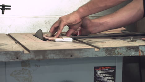 Level-sliding-shot-of-worker's-hands-shaping-a-piece-of-wood-with-a-table-sander