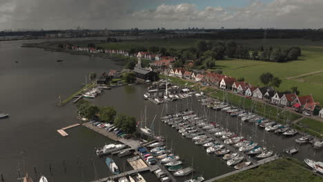 Aerial-pan-showing-the-marine-port-area-for-pleasure-boats-and-sailboats-with-typical-houses-of-the-Dutch-village-of-Durgerdam-at-the-Durgerdammerdijk-near-Amsterdam-with-clouds-casting-deep-shadow