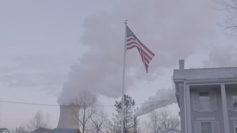 American-flag-in-foreground,-smoke-stack-behind