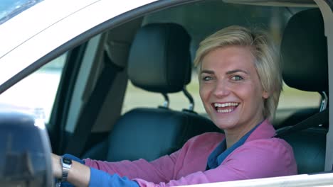 Portrait-of-an-attractive-business-woman-on-a-sunny-summer-day-sitting-behind-the-wheel-in-the-car-and-smiling-at-the-camera