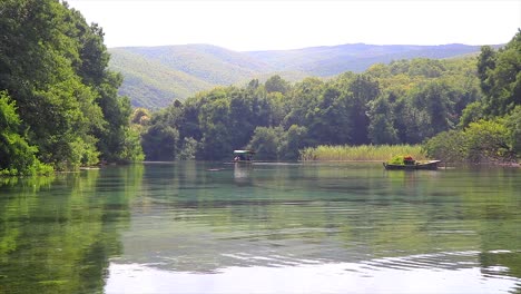 Agua-Cristalina-Y-Transparente-De-Un-Lago-Natural-Y-Un-Pequeño-Bote-De-Remos-Flotando-Lejos-Llevando-Turistas