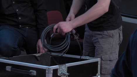Male,-sound-engineer,-puts-the-cables-in-a-black-hard-case
