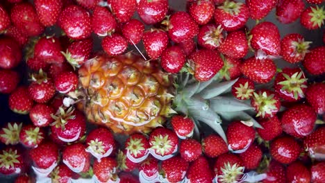 Pinapple-and-strawberry-fruit-spins-and-then-stop,-floating-in-water
